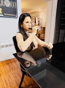 a woman sits at a table with a glass of wine in front of a poster that says 100000