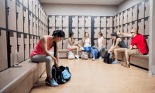 a woman sits on a bench in a locker room with a man pointing at the number 25