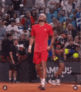 a man in a red shirt stands on a tennis court in front of a sign that says ' ampus universita '