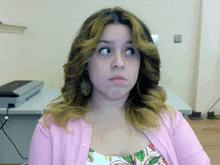 a woman in a pink cardigan is making a silly face