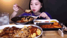 a woman is sitting at a table with plates of food and a wooden cutting board with the word wood on it