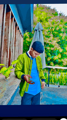 a man wearing a green jacket and a blue shirt looks at his phone