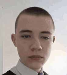 a young boy with a shaved head is wearing a white shirt and tie .