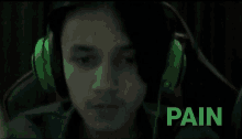 a man wearing green headphones has the word pain written below him