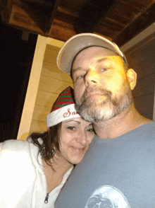 a man and a woman are posing for a picture with the woman wearing a santa hat