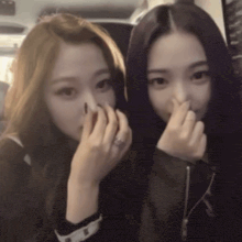 two girls are covering their faces with their hands and one has a ring on her finger