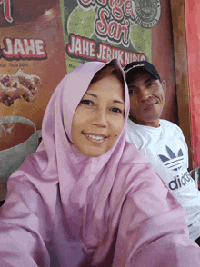 a man and woman are posing for a picture in front of a sign that says jahe jeruk nipis