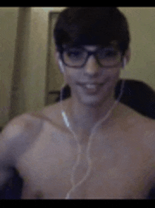 a shirtless man wearing glasses and headphones is smiling while taking a selfie .