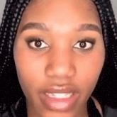a close up of a woman 's face with braids looking at the camera .