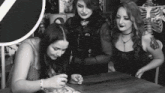 three women are sitting at a table looking at a piece of paper
