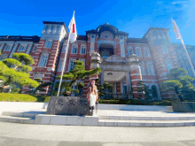 a woman stands in front of a large brick building with a sign that says " tokyo station "