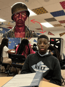 a boy wearing a reef sweatshirt sits at a table