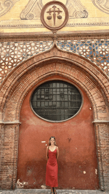 a woman in a red dress is standing in front of a red building