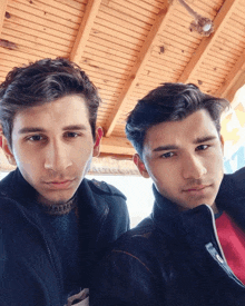 two young men are posing for a picture with a wooden ceiling in the background