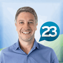 a man in a blue shirt smiles with a speech bubble with the number 23 on it