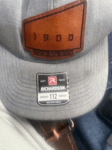 a grey richardson hat with a brown leather patch on the front