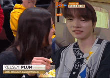 a woman eating popcorn next to a man with the name kelsey plum on his shirt