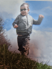 a young boy wearing sunglasses jumps in the air