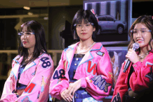 three women wearing pink jackets with the number 48 on them