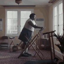 a man is standing on a treadmill in front of a window with a poster on the wall that says " the healthy diet "