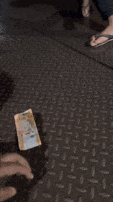 a person is holding a piece of money in their hand on a metal floor .