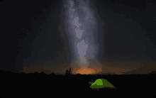 a green tent is lit up in the dark under a starry sky