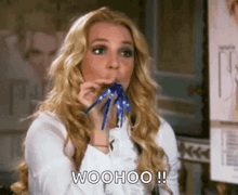 a woman is blowing a party horn and saying woohoo !