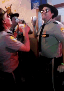 a man in a sheriff 's uniform drinks from a cup in front of a sign that says bud light