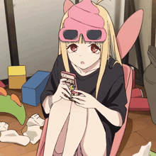 a girl wearing a pink hat and sunglasses is holding a phone