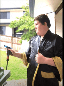 a man in a black and gold robe is holding a water hose