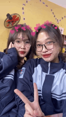 two girls are posing for a picture with hearts on their faces and one of them is wearing glasses