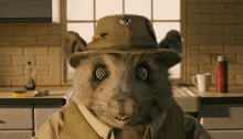 a mouse wearing a hat and vest looks at the camera with hypnotic eyes