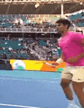 a man in a pink shirt is holding a tennis racquet