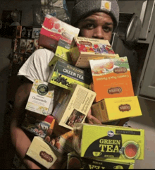 a man is holding a pile of green tea boxes