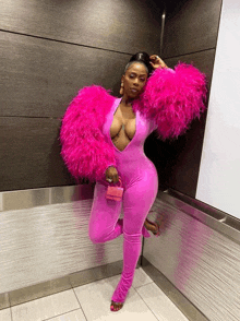 a woman is wearing a pink jumpsuit with feathered sleeves and a pink purse .