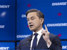 a man in a suit and tie is giving a speech in front of a wall that has the word change on it