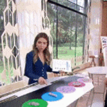 a woman in a blue jacket is standing in front of a table with a bunch of plates on it .