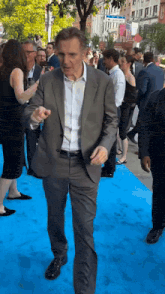 a man in a suit is walking down a blue carpet