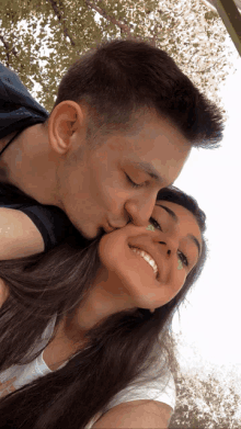 a man kisses a woman on the cheek while she smiles for the camera