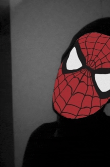a person wearing a spider man mask with a black background
