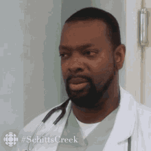 a man in a lab coat with a stethoscope around his neck has #schitts creek written on the bottom right
