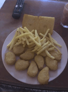 a plate of nuggets and french fries on a table with a samsung remote in the background