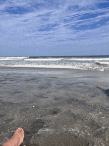 a person 's feet on a sandy beach with a blue sky in the background