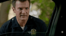 a man in a police uniform is looking out the window of a car