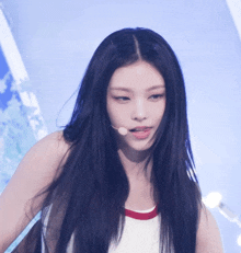 a woman with long black hair is wearing a white top and a microphone in her mouth