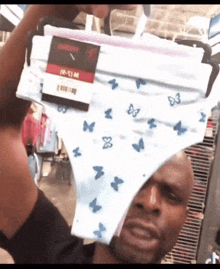 a man holds up a pair of underwear with blue butterflies on them