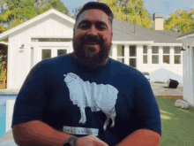 a man with a beard wears a blue shirt with a picture of a sheep on it