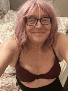 a woman with pink hair and glasses is smiling