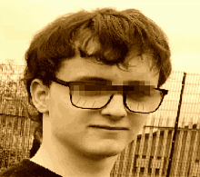 a young man wearing glasses looks at the camera