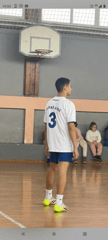 a man wearing a number 3 jersey stands in front of a basketball hoop